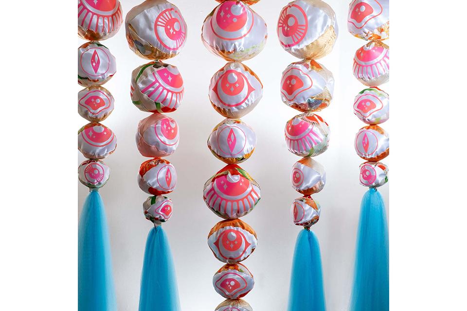 five rows of pink and white balls strung in a row vertically with a blue tassel at the bottom